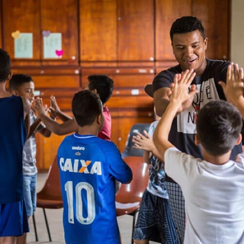 An adult volunteer receives a high five during some time in a gymnasium. Photo courtesy Connectional Table.