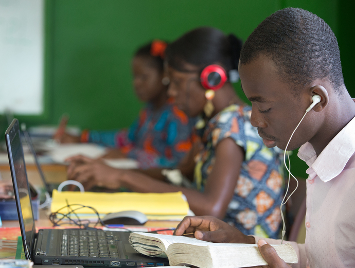 Lionel Sahuie (right) prepares a story in the newsroom at The Voice of Hope.