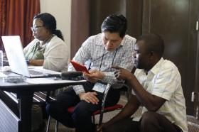 Danny Mai (center) helps Isaac Kunda Muke with a question during the training for Congolese church communicators. Mai and Shelia Mayfield (far left) were part of the team from United Methodist Communications, which held the training. Photo by Kathleen Barry, UMNS