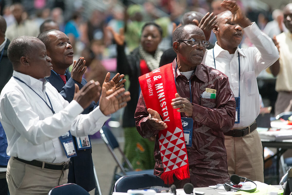 Michel Lodi of the East Congo Conference (right foreground) joins other African delegates in singing during a recess at the 2016 United Methodist General Conference in Portland, Ore. Church leaders say visa problems are causing a struggle to get delegates from outside the U.S. to the General Conference that begins April 23 in Charlotte, N.C. African United Methodist groups warn that their region could be significantly underrepresented. File photo by Mike DuBose, UM News.